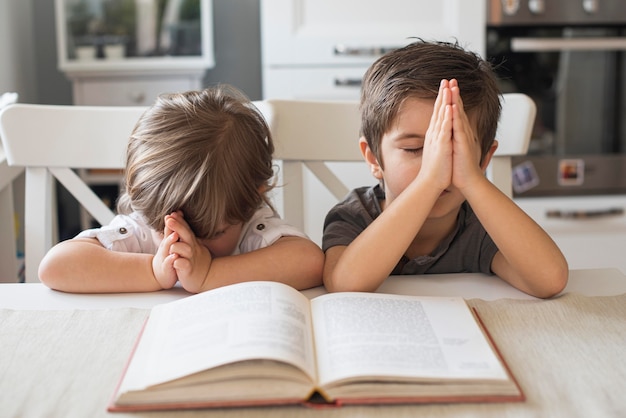 cute children praying together at home