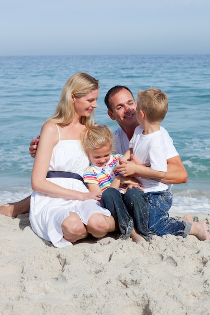 Cute children and their parents sitting on the sand