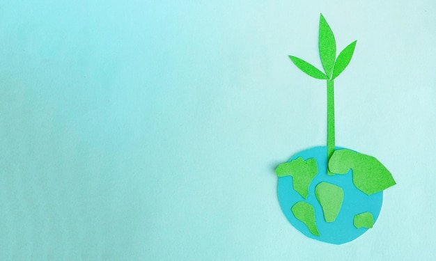 Cute childrens paper applique a model of the Earth and a young sprout on a blue background Creative concept Earth Day Earth Hour copy space for text