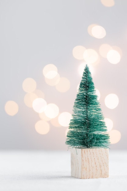 Cute Christmas miniature fir tree on a white table with bokeh lights