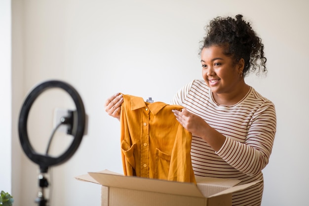 Cute chubby woman fashion blogger showing brand clothes unpacking parcel
