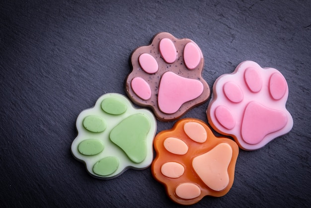 Cute colored paw shape soap on dark dark . Dark 