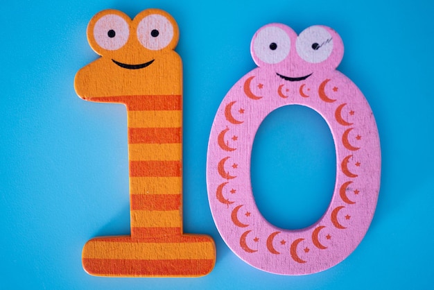 Photo cute and colorful wooden number 10 with eyes on a blue background