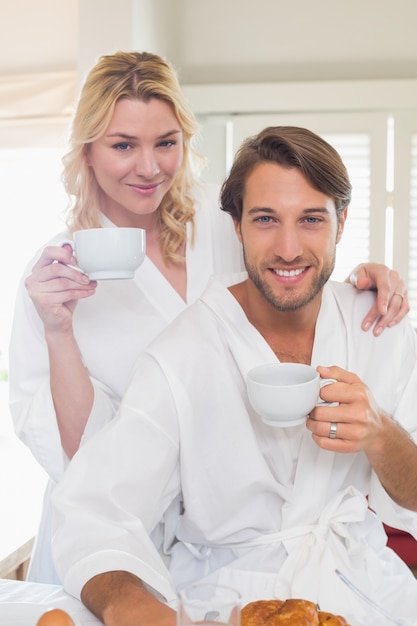 Cute couple in bathrobes having breakfast together