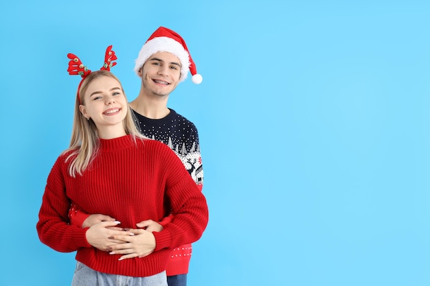 Cute couple in Christmas clothes on blue background