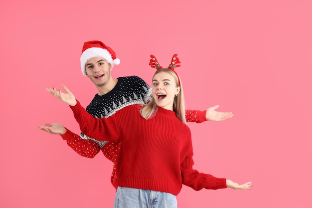 Cute couple in Christmas clothes on pink background