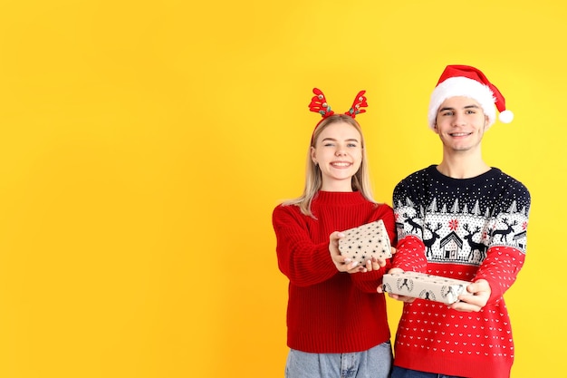 Cute couple in Christmas clothes on yellow background