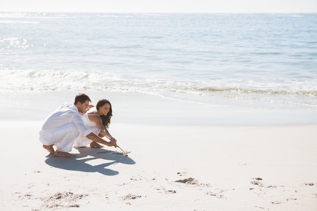 Cute couple drawing in the sand