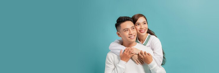 Photo 밝은 파란색 배경에 카메라를 바라보며 포옹하는 귀여운 커플