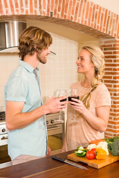 Coppie sveglie che godono di un bicchiere di vino nella cucina