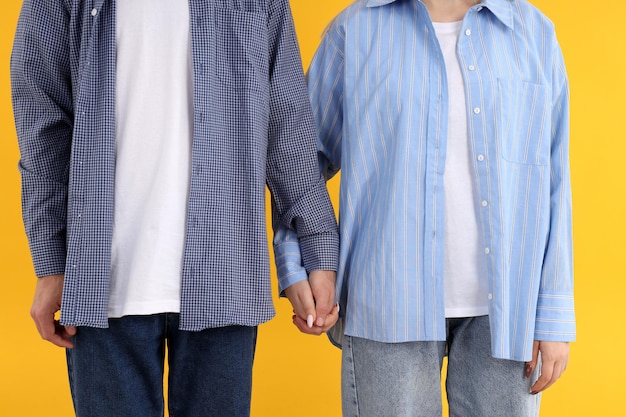 Cute couple holding hands on yellow background