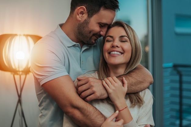 Cute couple hugging and smiling in their new home.