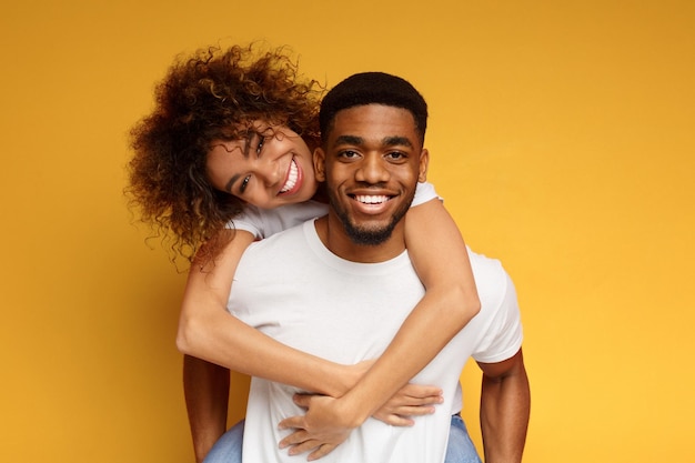 Cute couple in love embracing on orange background