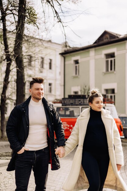 A cute couple in love in outerwear is walking on the street in spring Recreation together in the open air Young stylish couple