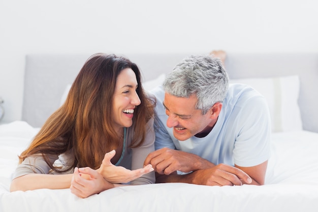 Cute couple lying on bed talking together