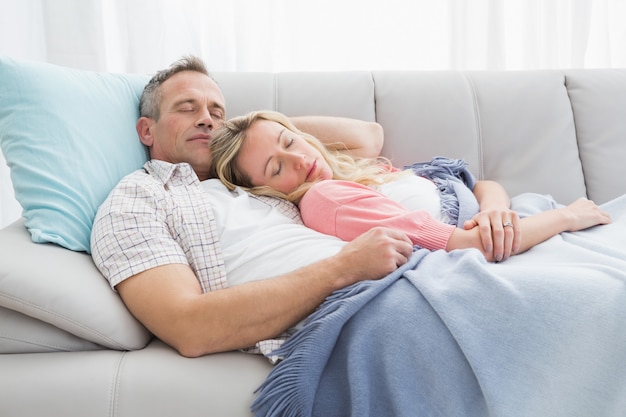 Cute couple napping under a blanket on the couch