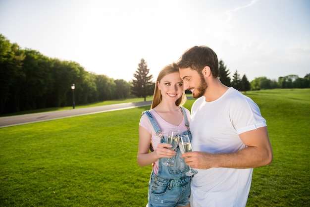 Cute couple posing together outdoors with champagne