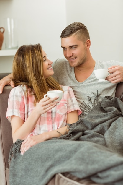 Cute couple relaxing on couch with coffee