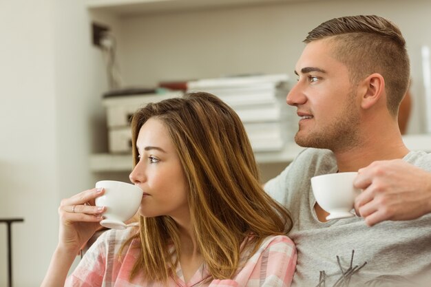 Cute couple relaxing on couch with coffee