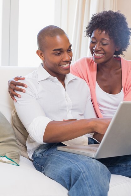 Cute couple relaxing on couch with laptop