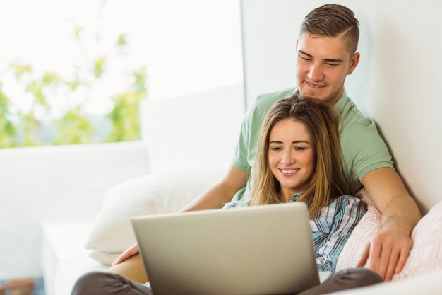 Cute couple relaxing on couch with laptop