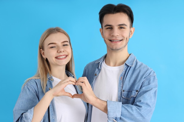 Cute couple showing love sign on blue background