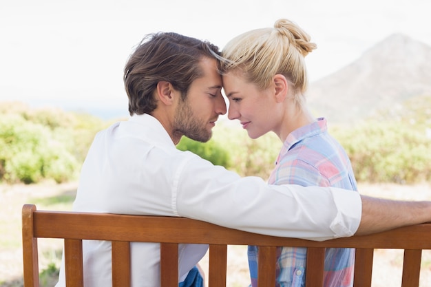 Cute couple sitting on bench together smiling at each other