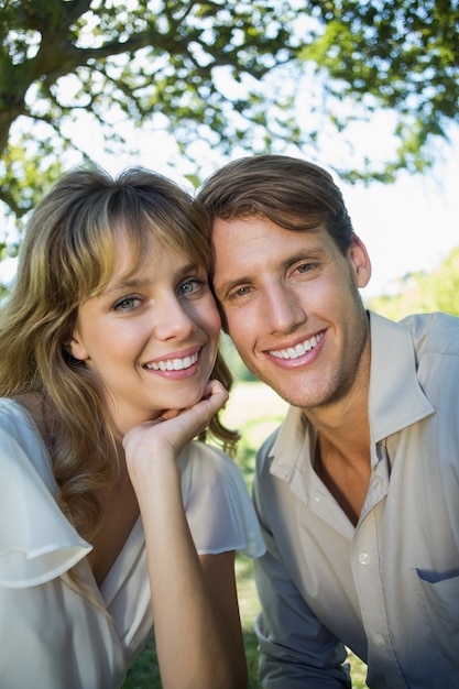 Photo cute couple sitting outside at a cafe smiling at camera