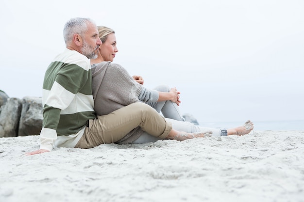 Photo cute couple sitting in the sand