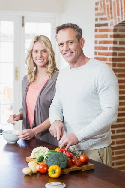 Cute couple slicing vegetables in the kitchen