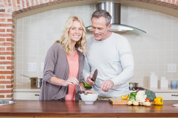 Cute couple slicing vegetables in the kitchen