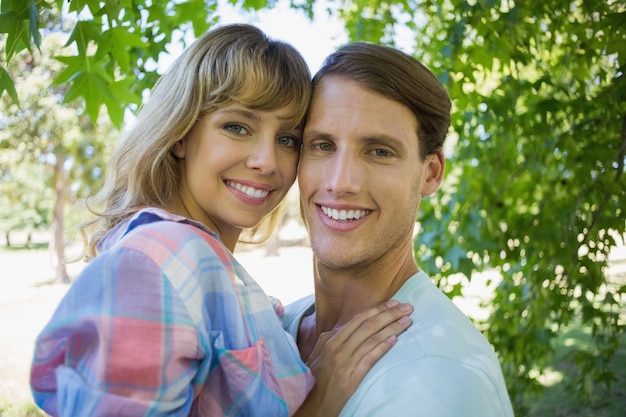 Cute couple smiling at camera and hugging in the park