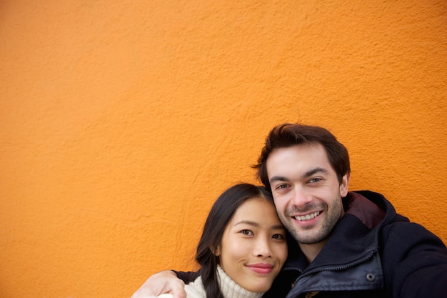 Cute couple smiling on orange background