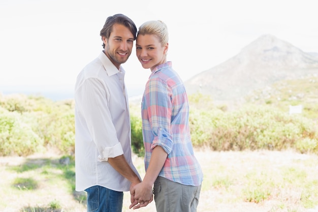 Cute couple standing hand in hand smiling at camera