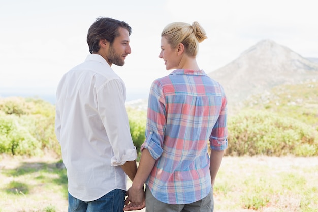 cute couple standing hand in hand smiling at each other