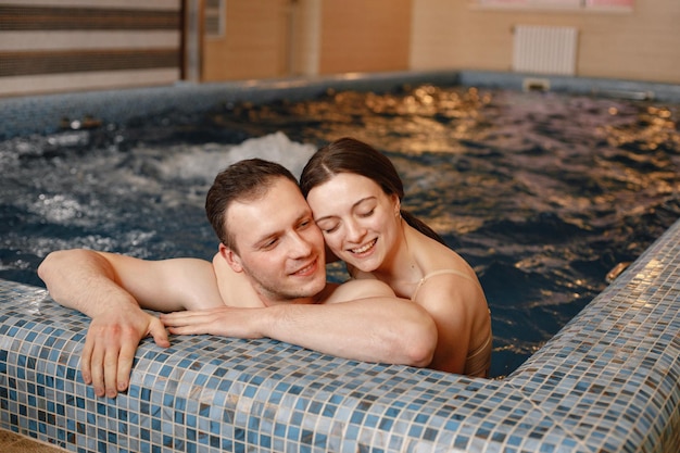 Cute couple talking and hugging near poolside in indoors swimming pool