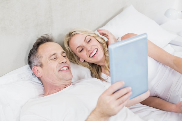 Cute couple using tablet in bed