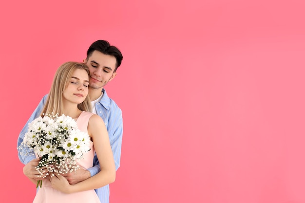 Cute couple with bouquet on pink background