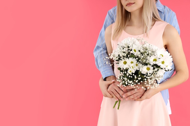 Cute couple with bouquet on pink background