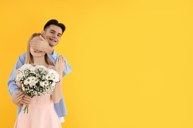 Cute couple with bouquet on yellow background