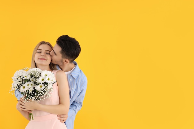 Cute couple with bouquet on yellow background