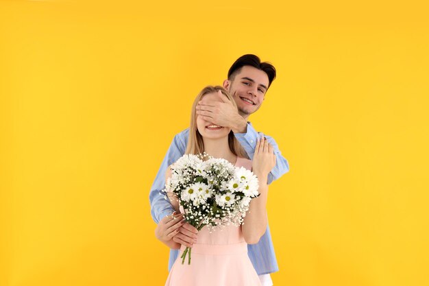 Cute couple with bouquet on yellow background