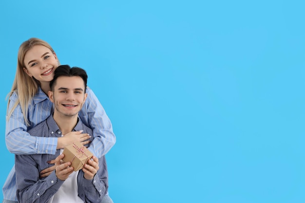 Cute couple with gift box on blue background