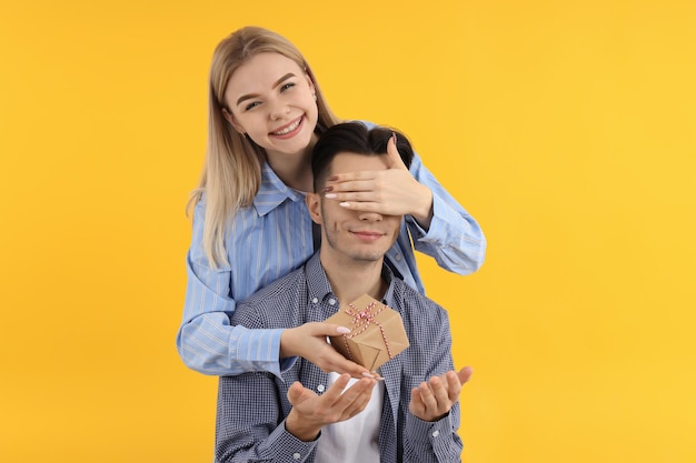 Cute couple with gift box on yellow background