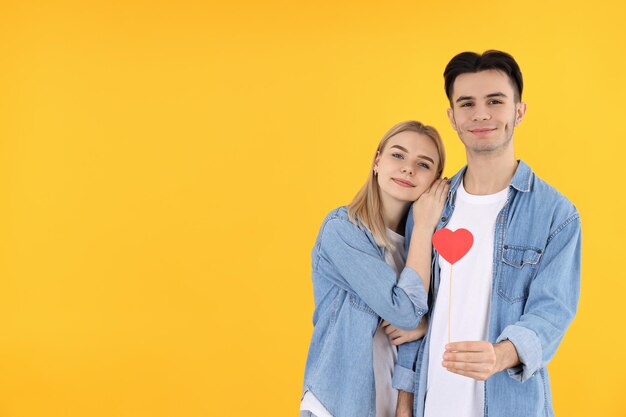 Cute couple with heart on yellow background