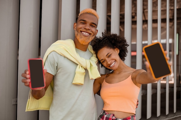 A cute couple with smartphones in hands feeling good