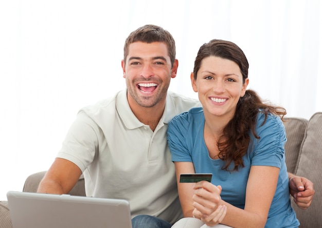 Cute couple with their laptop and credit card sitting in the living room