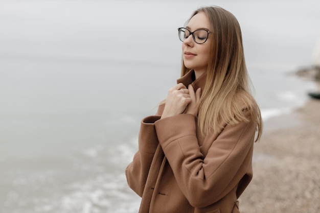 海の近くの屋外のかわいい居心地の良い笑顔の女性