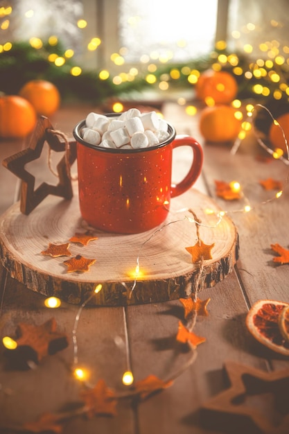 Фото Милая уютная зимняя композиция красная чашка маршмеллоу апельсины и рождественские огни