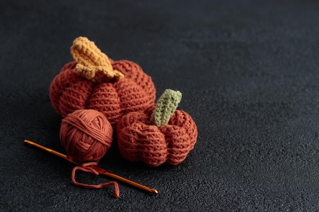 Cute crochet knitted orange pumpkins on black background